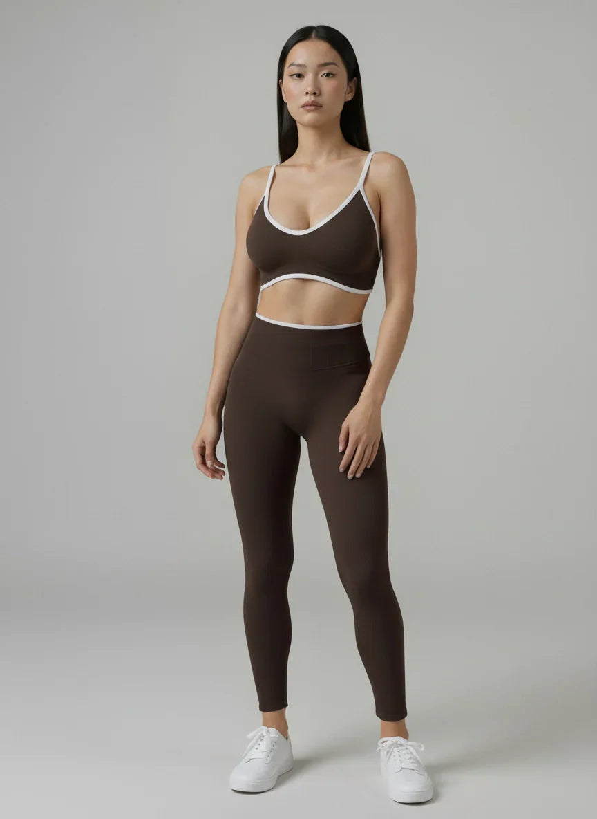 The Elevate Seamless Leggings in chocolate brown with white trim, paired with a matching sports bra for sleek activewear.