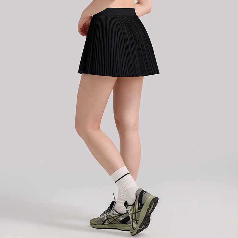 Black pleated tennis skirt with built-in shorts, styled with athletic shoes for a sleek and functional activewear outfit.