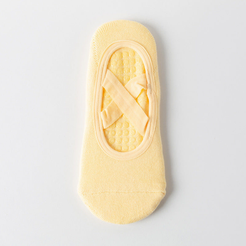 Cross-strap yoga sock in pastel yellow with 3D non-slip grip sole. Breathable, sweat-absorbent fabric ideal for stability during workouts.