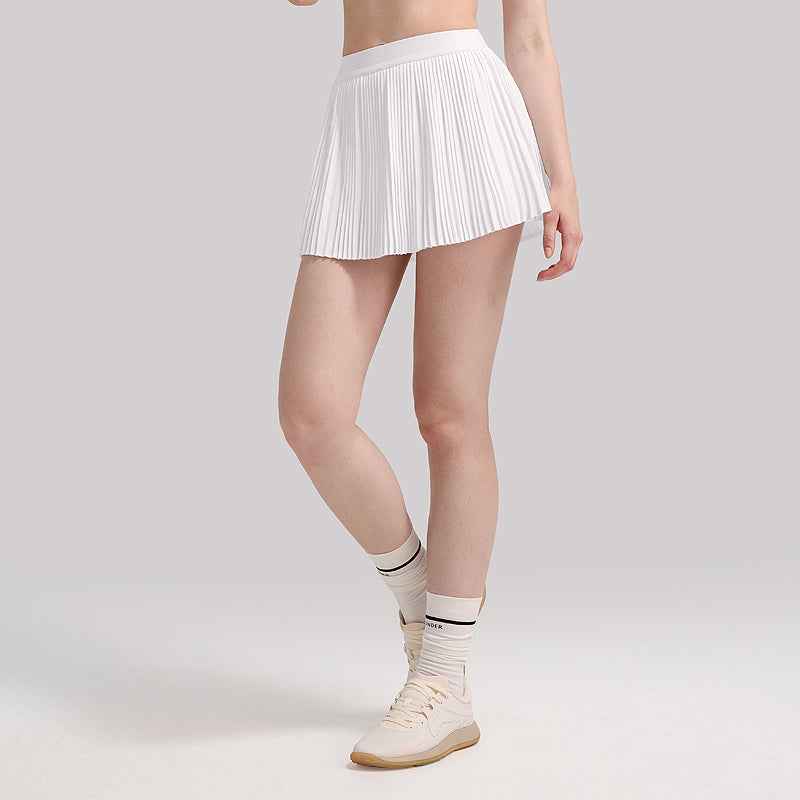 White Agile Pleated Lightweight Tennis Skirt with Built-In & Safety Shorts styled with socks and sneakers, ideal for court sports.